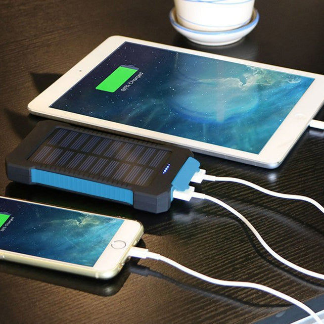 Solar power bank charging a smartphone and tablet on a dark surface