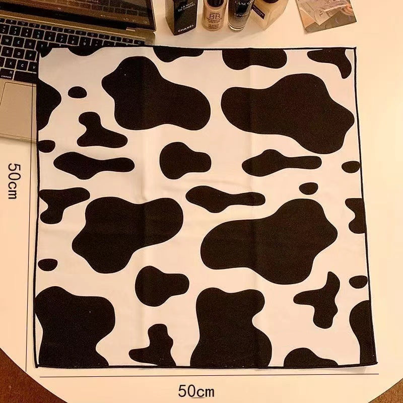 Cow print Magic Pet Wrap branding on a desk with a laptop and bottles.