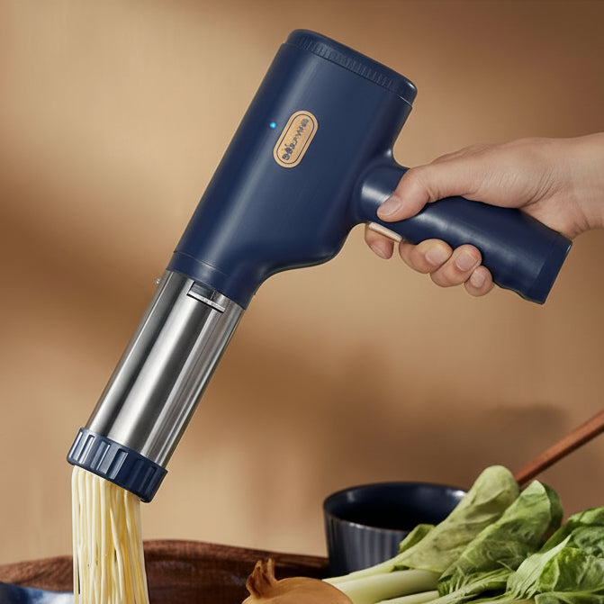 Handheld noodle maker being used to make noodles with a hand holding it, on a table with vegetables.